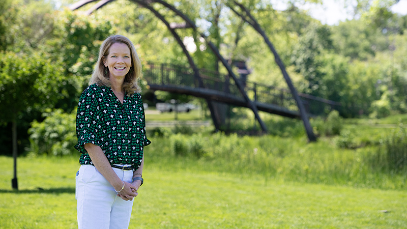 Woman standing in a park with a bridge in the background