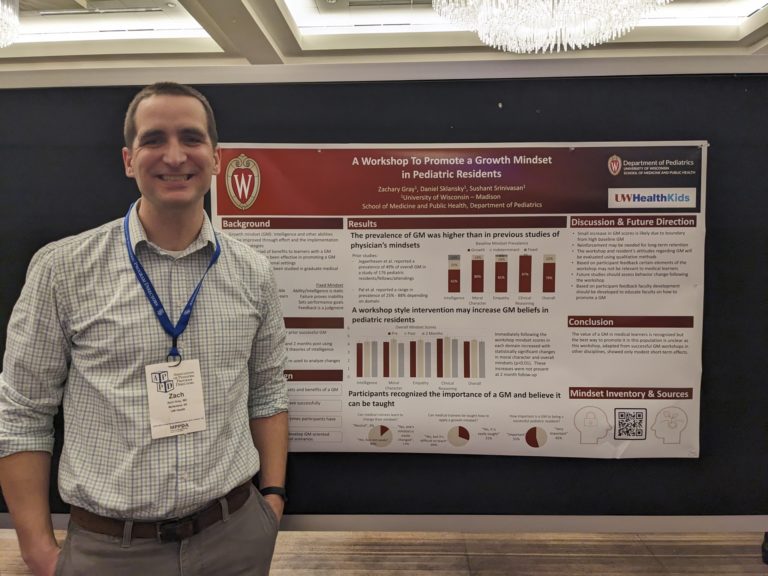 a smiling fellow standing in front of a poster titled "A Workshop to Promote a Growth Mindset in Pediatric Residents"