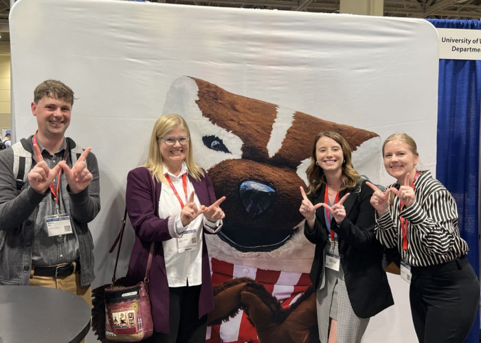 group of four people standing in front of Bucky Badger
