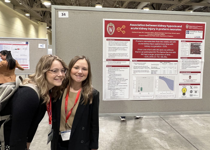 two women in front of a scientific poster in a conference hall
