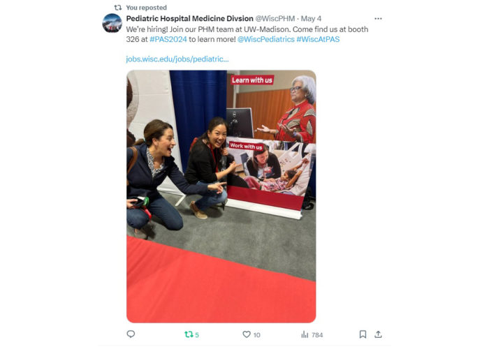 two women kneeling and pointing to a person on a banner