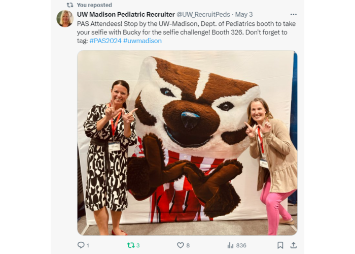 Two women with their hands making a W in front of Bucky Badger