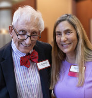Two people dressed in professional clothing looking at camera and smiling