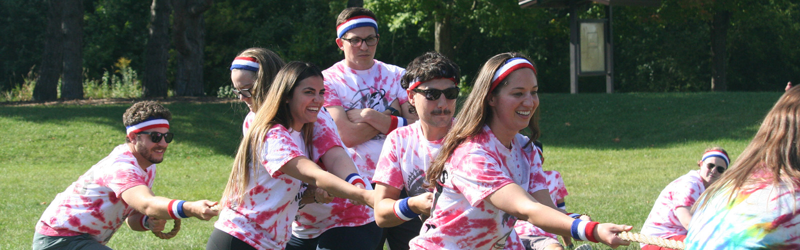 a team of residents in tie dyed shirts playing tug of war