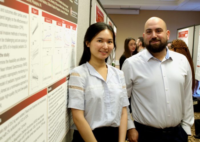 Two people standing next to a poster during a scientific poster presentation.