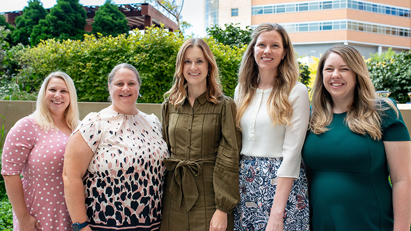 Five women standing in a row outside