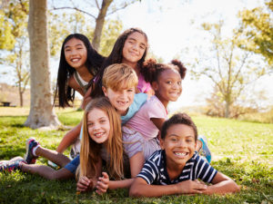 Group of kids lying on each other in a park.
