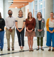 A group of health care providers standing in a row and looking at the camera.