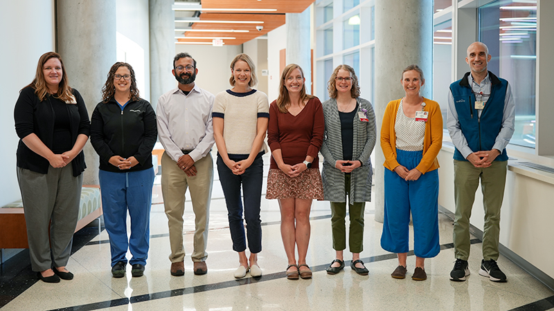 A group of health care providers standing in a row and looking at the camera.
