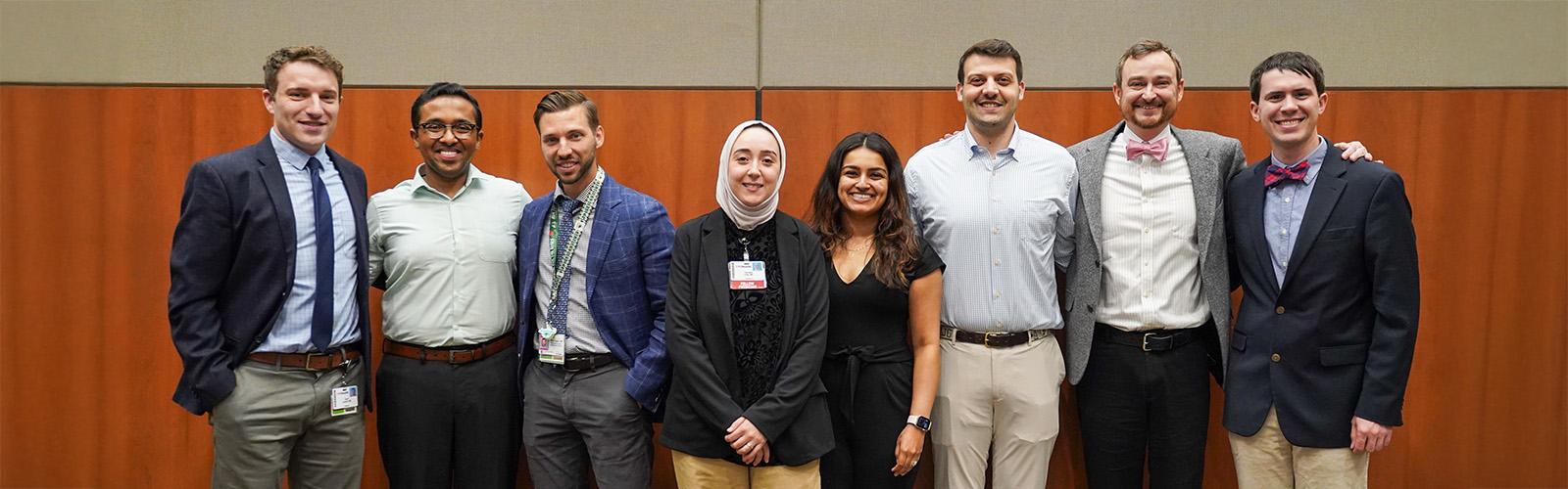 A group of eight people standing in a row and smiling at the camera.