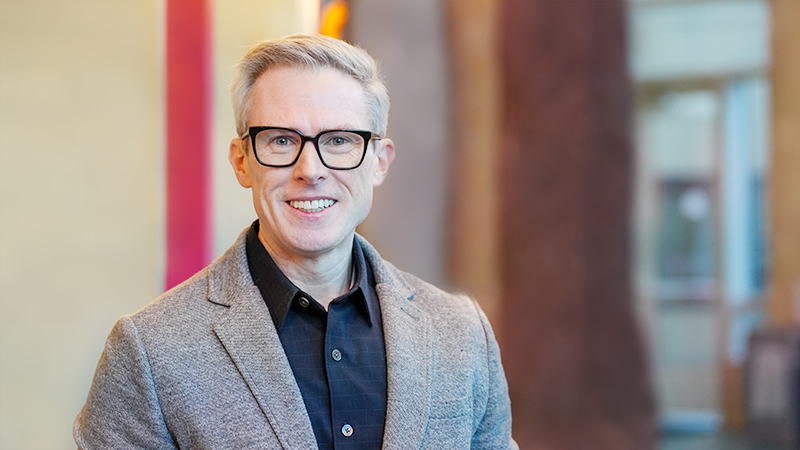Dr. Daniel O'Connell wears a gray suit jacket and smiles at the camera.