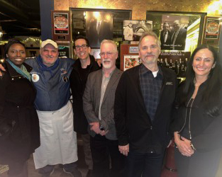 A group of people standing in a restaurant.