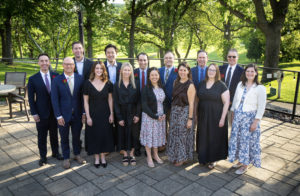 Group of people wearing semi-formal wear and standing outside in a group posing for the camera.