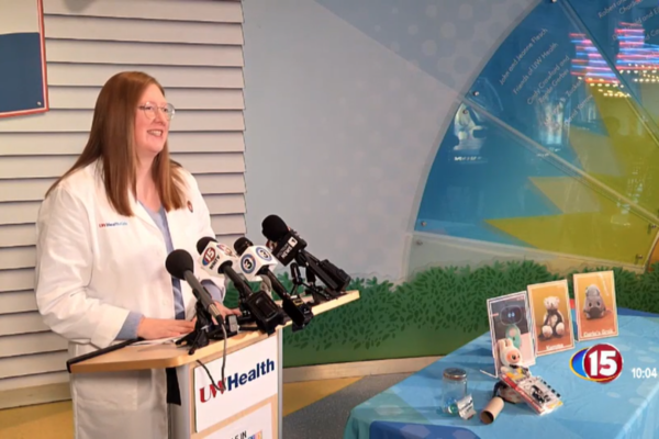 Dr. Megan Yanny presenting behind a podium with several microphones.