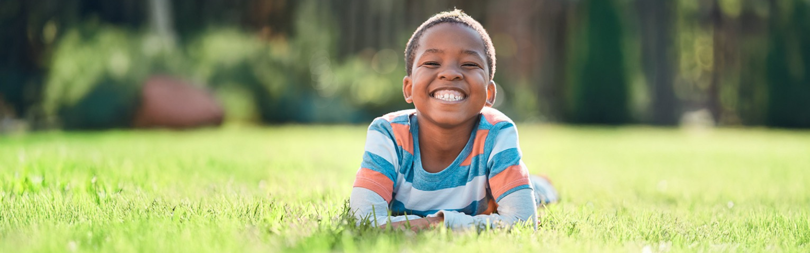Boy laying in grass while smiling