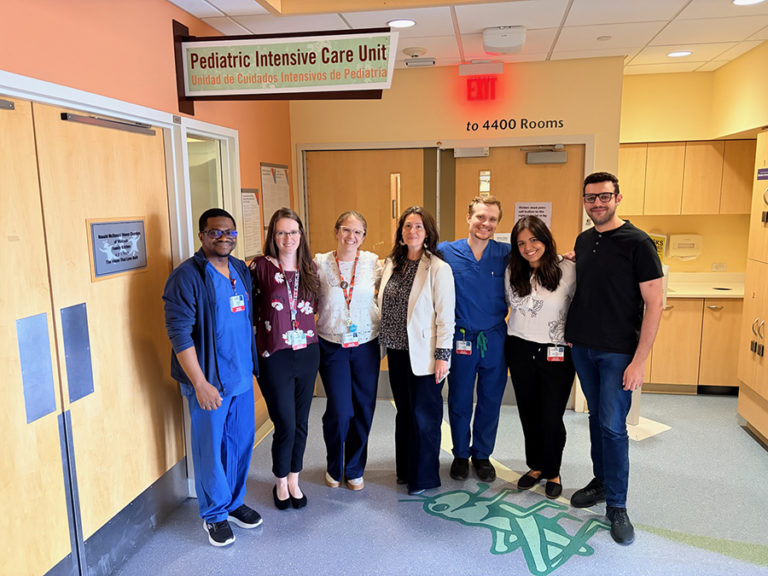 A group of doctors standing under a sign that reads Pediatric Intensive Care Unit.