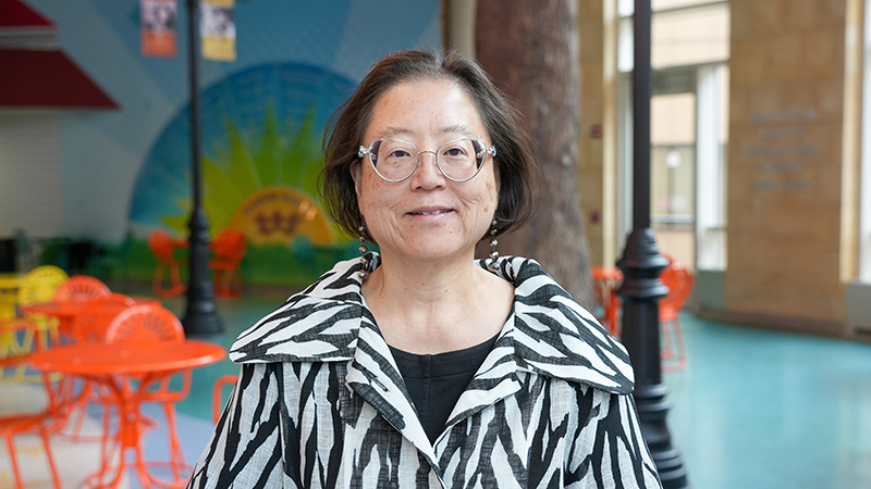 Dr. Katryn Furuya wearing a black and white print shirt with the American Family Children's Hospital atrium in the background.