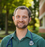 Dr. Andrew Lewandowski standing outside with a stethoscope around his neck.