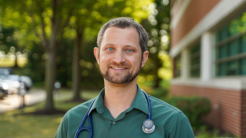 Dr. Andrew Lewandowski standing outside with a stethoscope around his neck.