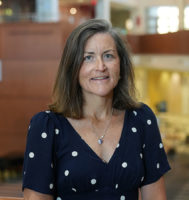 Dr. Margret Bock posing for a photo with an atrium behind her.