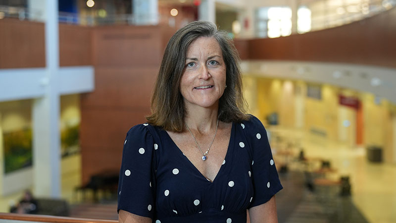 Dr. Margret Bock posing for a photo with an atrium behind her.