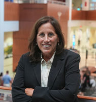 Dr. Mary Nevin is wearing a black blazer and posing for the camera with her arms crossed.